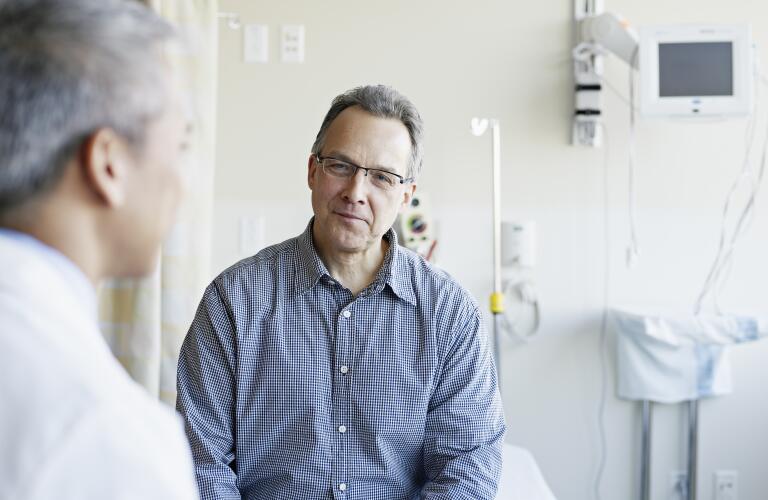 Doctor talking to male patient in hospital room
