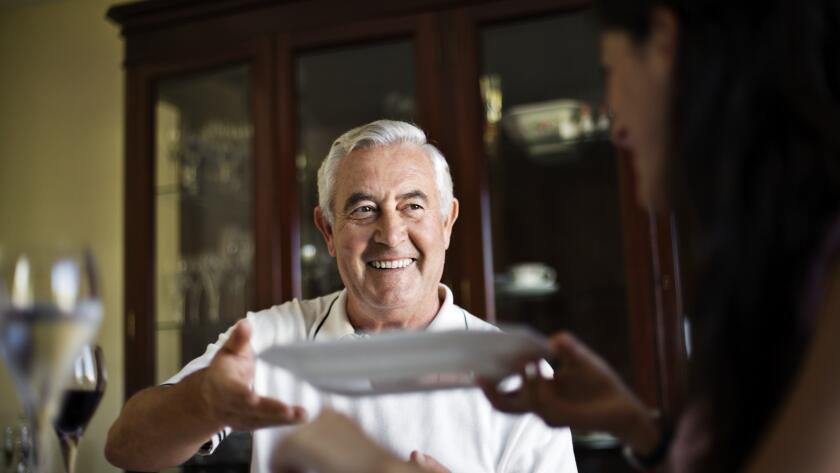 smiling man reaching for dinner plate