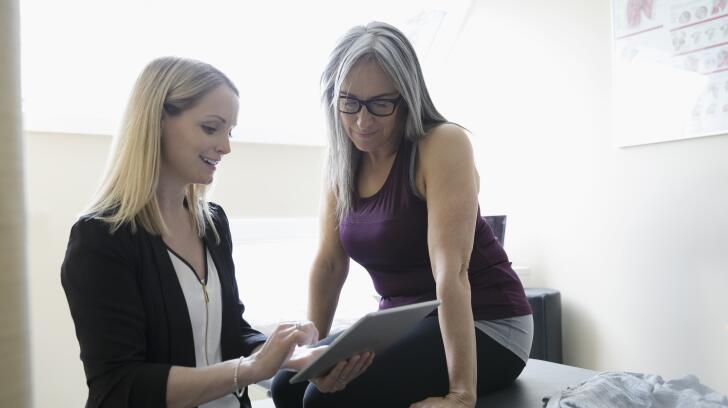 female patient looking at tablet with doctor