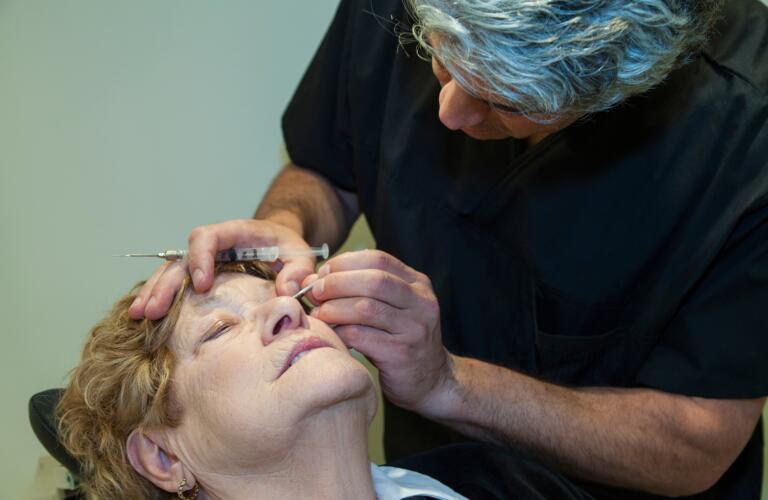 Caucasian male eye doctor giving Caucasian female patient eye injection