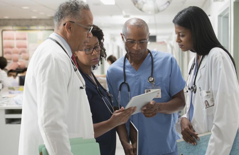 team of doctors and nurses in circle reviewing medical chart