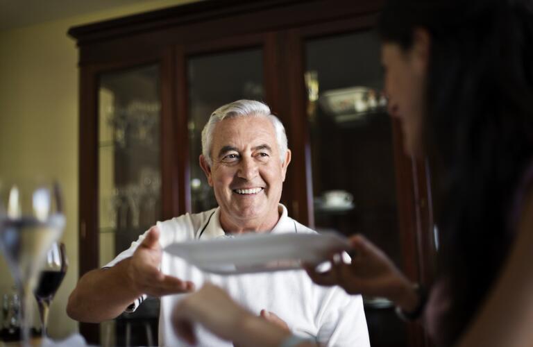 smiling man reaching for dinner plate