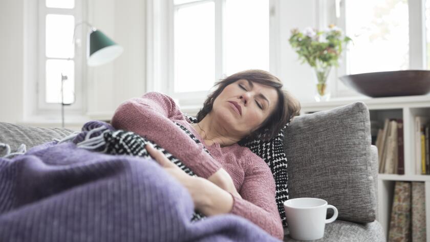 Middle aged woman on couch with stomach pain
