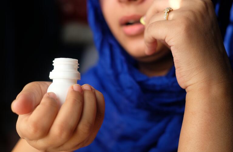 Close-up of woman's hands taking medication from pill bottle