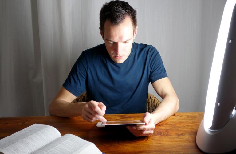 young man looking at digital tablet device near light therapy lamp