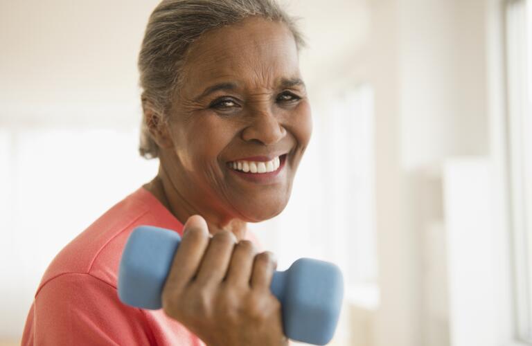 portrait of smiling senior woman lifting hand weight