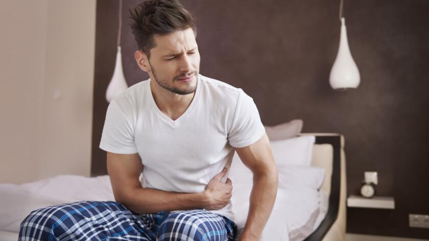 man-sitting-on-bed-with-stomachache