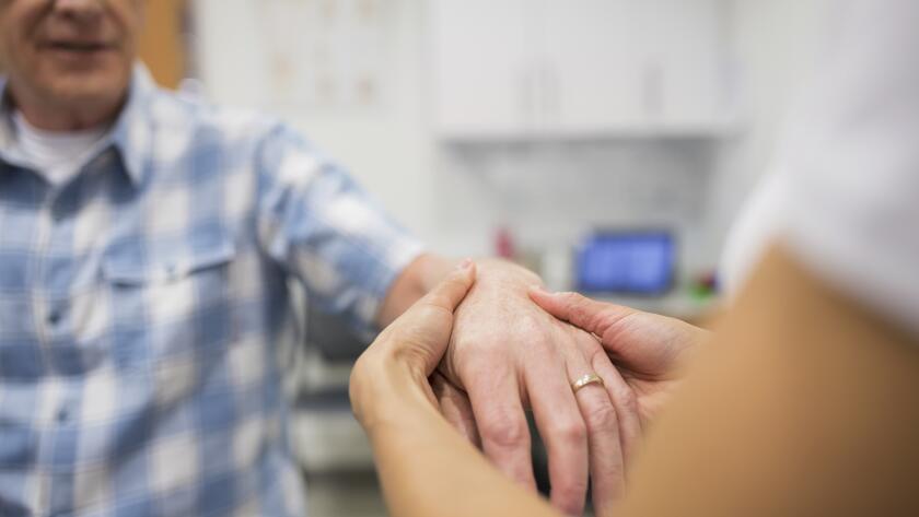 closeup of doctor or physical therapist feeling back of patient hand