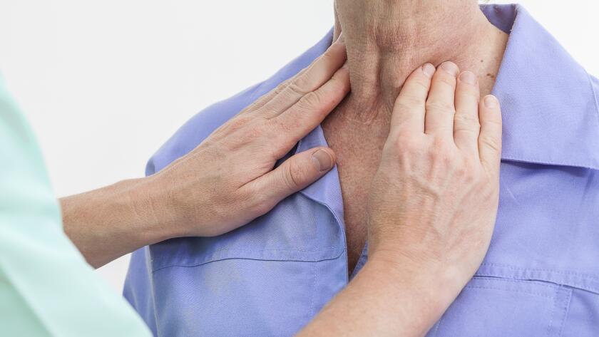doctor examining female patient's thyroid