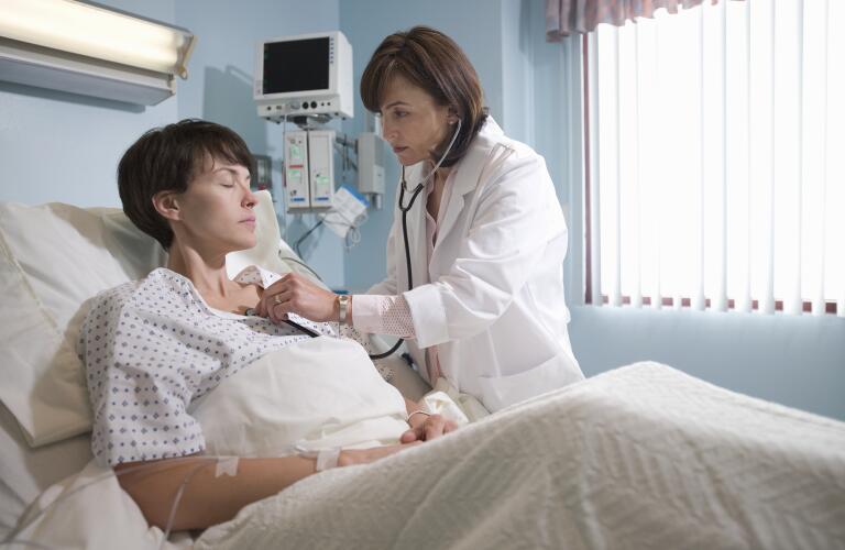Female doctor at hospital checking female patient's heart with stethoscope