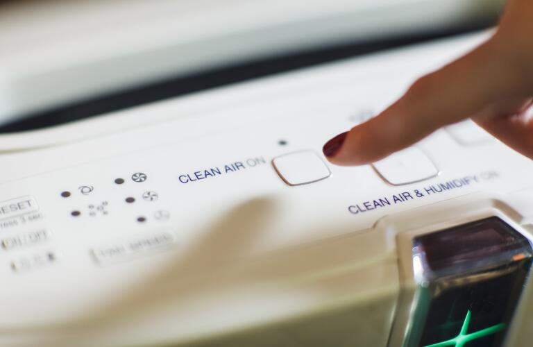 Close-up of woman's finger turning on air purifier power button