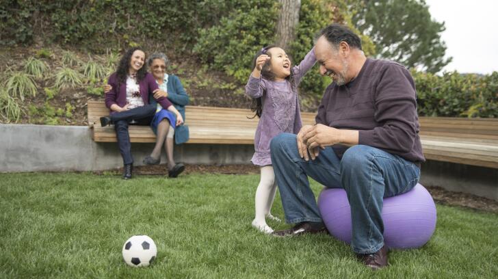 Grandfather playing in park with granddaughter