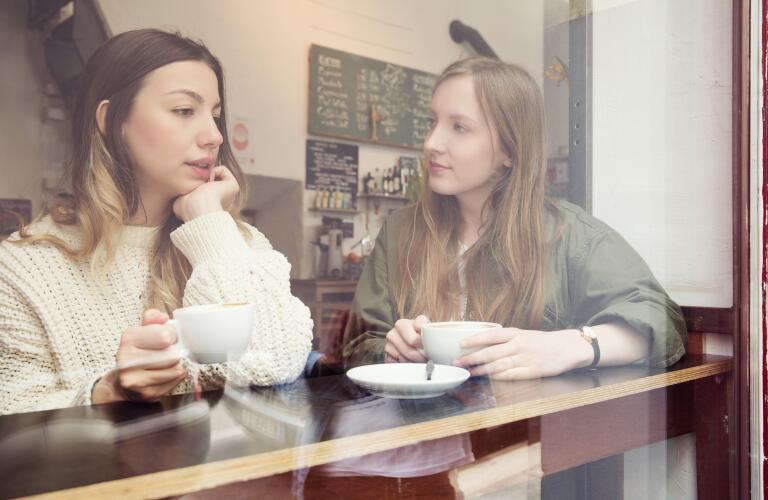 Two young Caucasian women in serious conversation at coffee shop