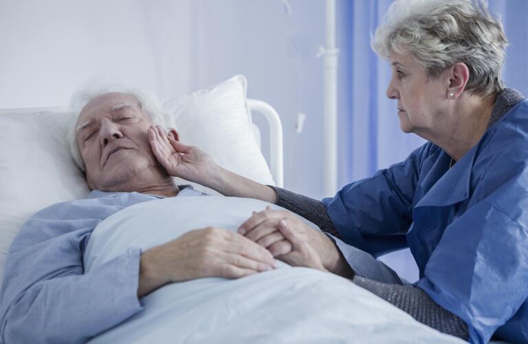 Caucasian wife comforting unconscious husband in hospital