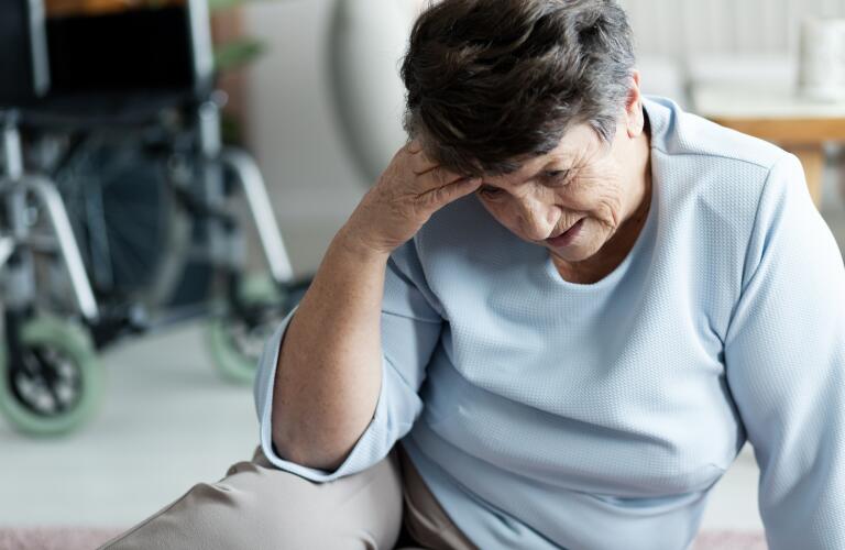 Senior woman in hospital or exam room holding head in pain