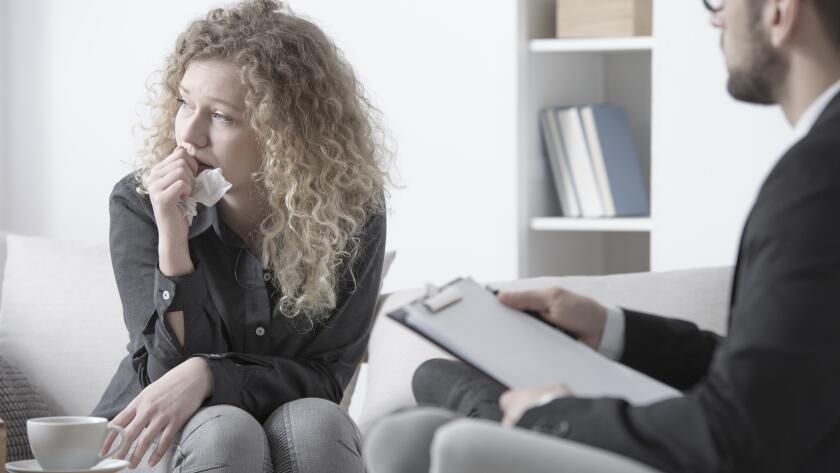Young Caucasian woman crying and staring while talking to counselor or therapist
