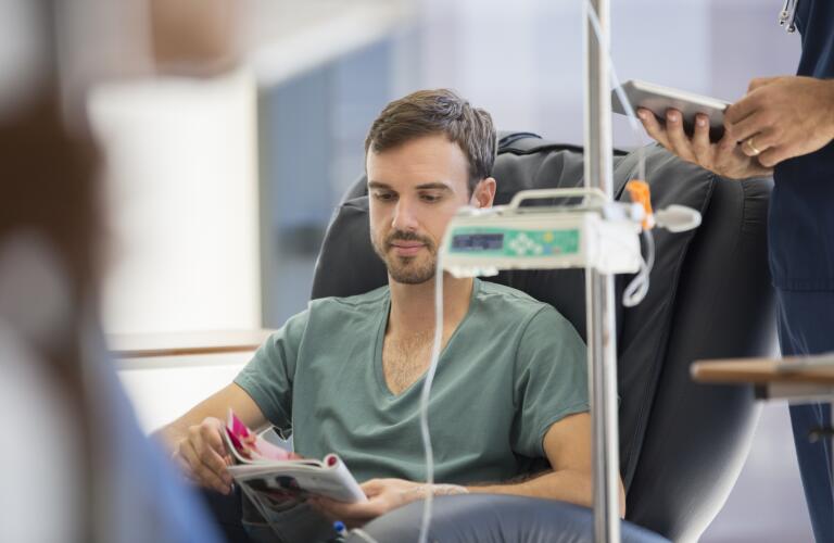 Patient reading magazine, undergoing medical treatment in outpatient clinic