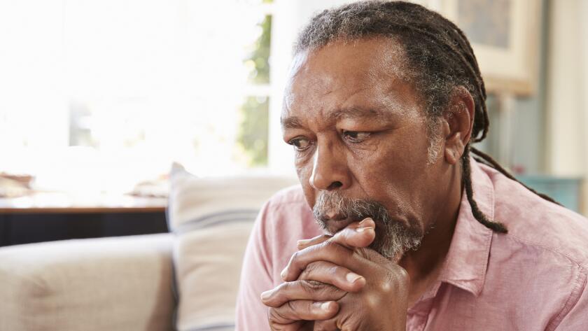 serious senior african american man sitting on couch