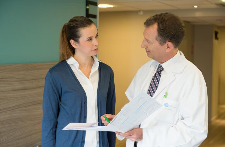 Male doctor discussing medical report with a woman in hospital