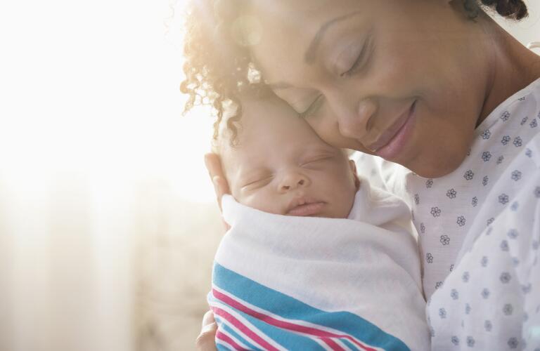 Mother with newborn infant smiling with eyes closed