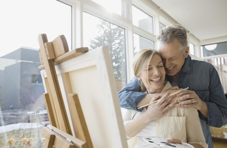 Middle aged woman painting art and smiling with husband