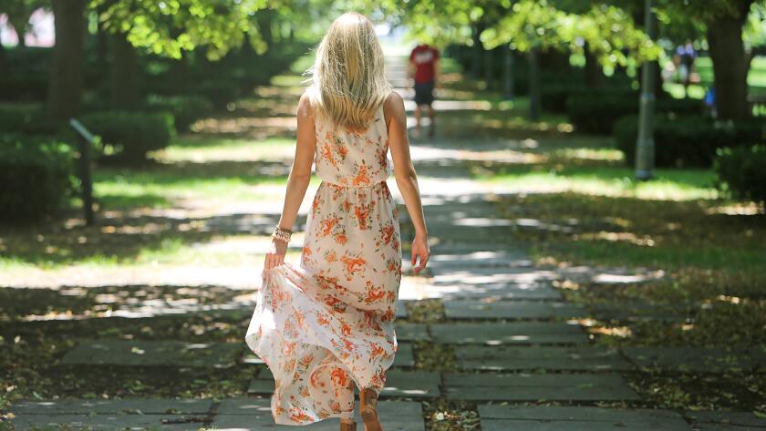 unidentified blonde woman walking away from camera down park path
