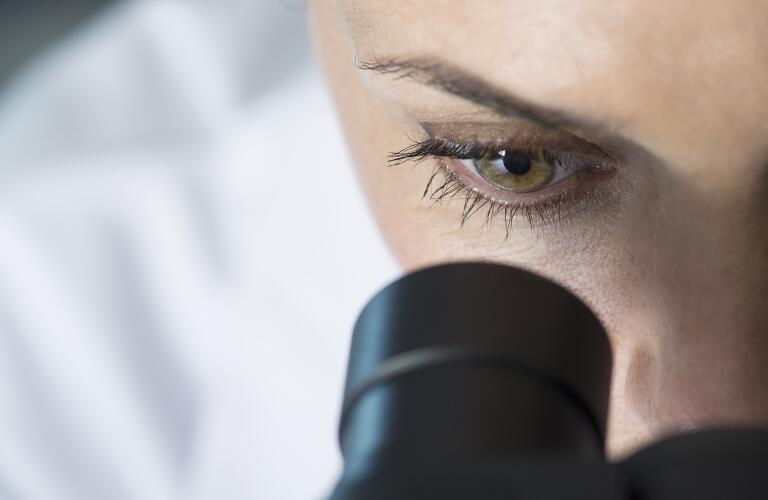 unidentified woman peering into microscope