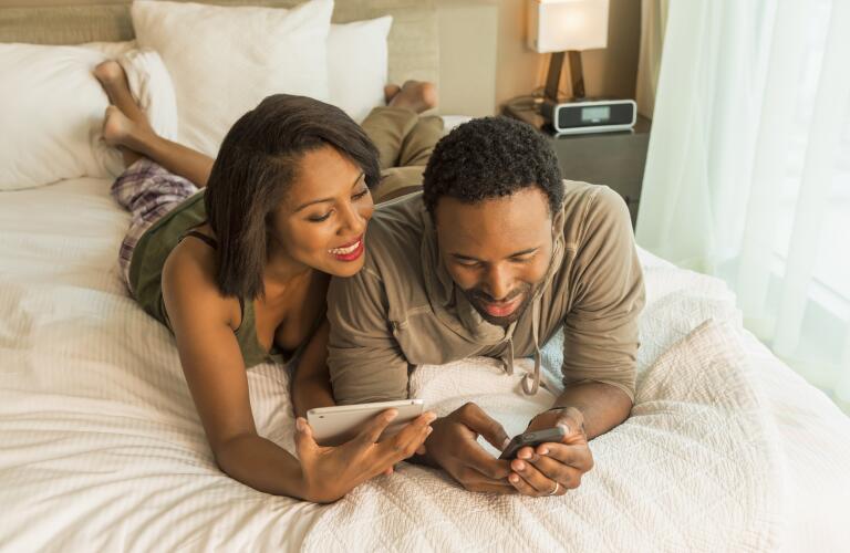 couple-talking-in-bed-looking-at-devices