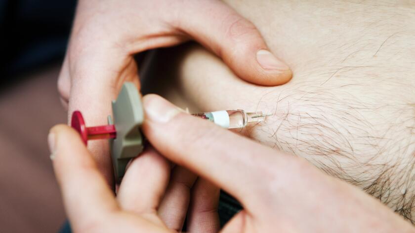 closeup of man giving himself an injection of biologic drug into his stomach