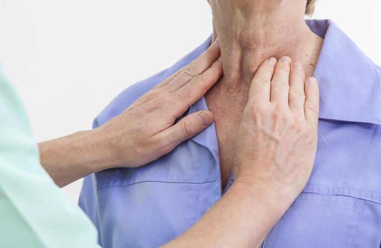 doctor examining female patient's thyroid