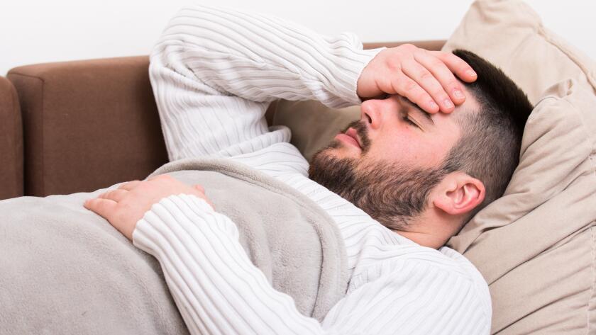 man with hand on head lying on couch