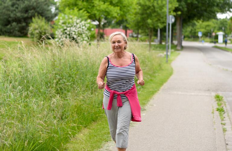 senior woman exercising down street outside