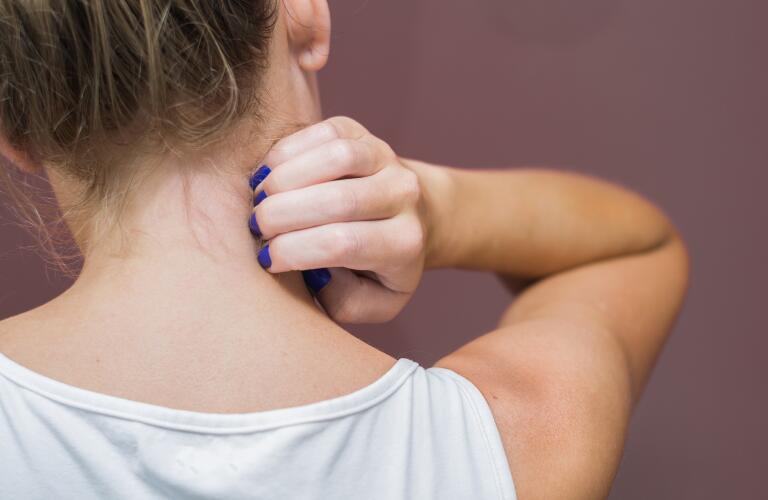 Caucasian woman scratching back of neck