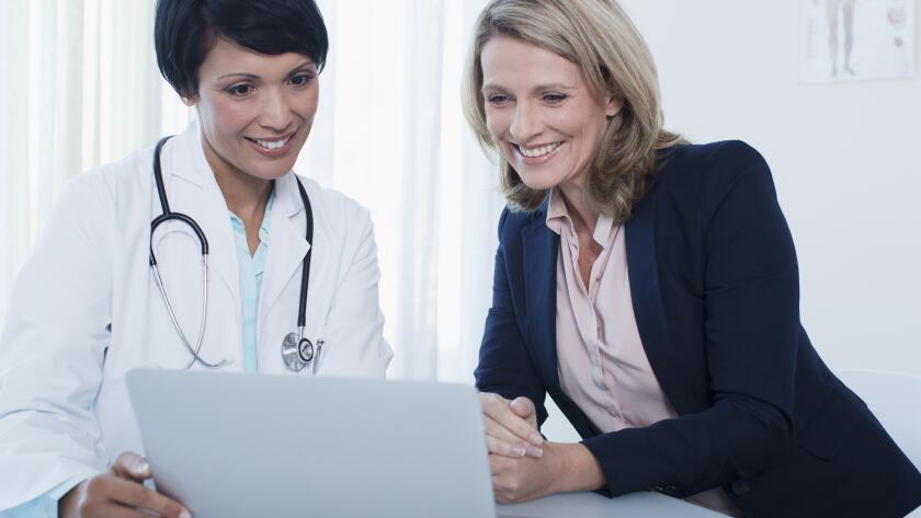 Doctor and patient using laptop in hospital office
