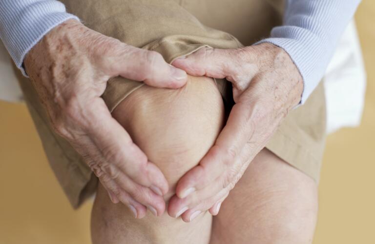 senior woman holding sore knee with arthritis