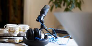 Podcast microphone and headphones set up near laptop on desk