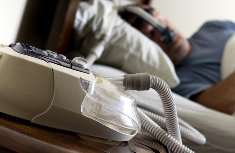 Man Sleeping in Bed with Sleep Apnea Maks