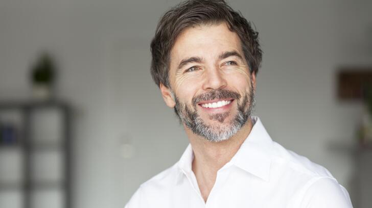 Уверенный в себе мужчина улыбается и смотрит в сторону