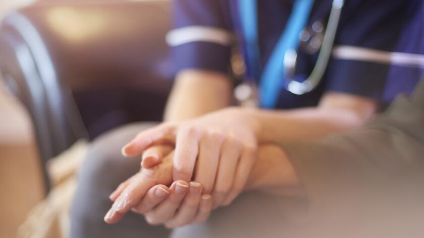 nurse consoling patient by holding hand