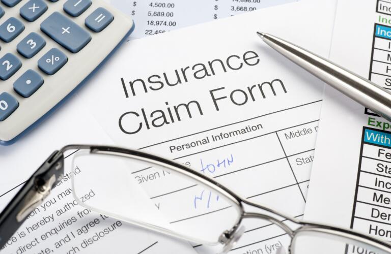 Handwritten Insurance Claim Form with pen and calculator
