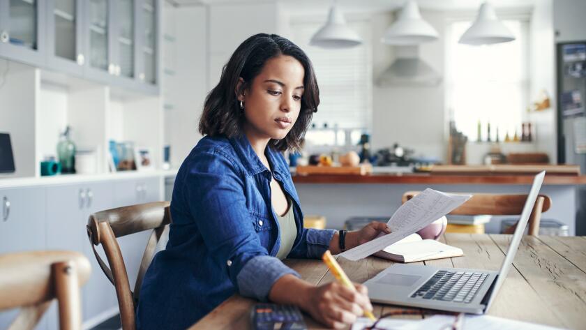 Young Hispanic woman working on laptop in home kitchen