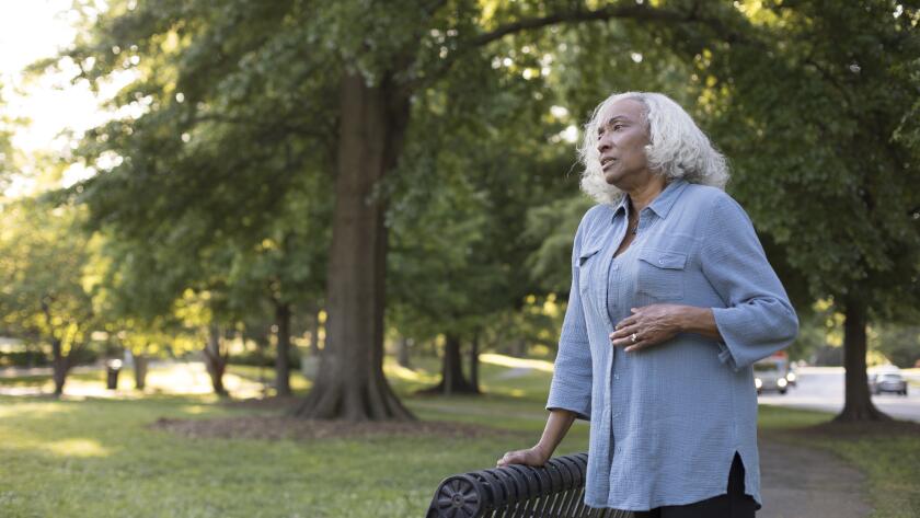 Senior African American woman in park with hand on stomach