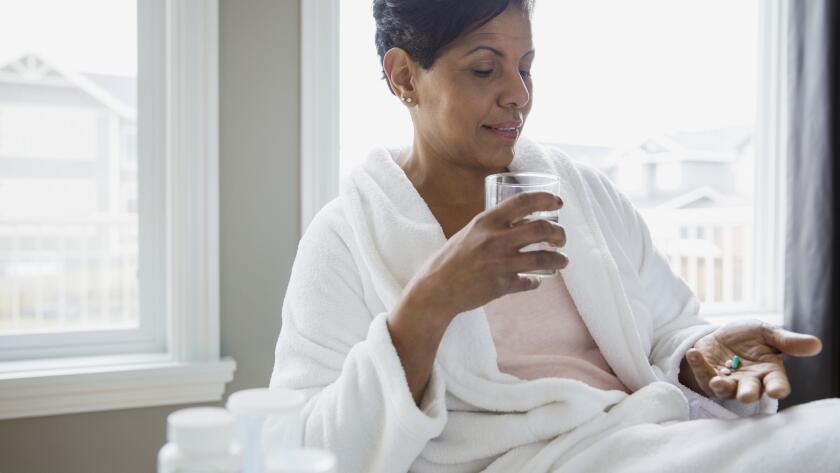 woman in bathrobe taking vitamins or medication