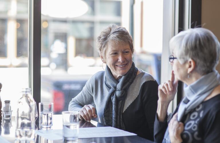 two senior Caucasian women talking at restaurant table during lunch
