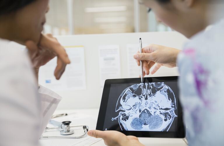 Doctor and nurse examining CT scan digital tablet