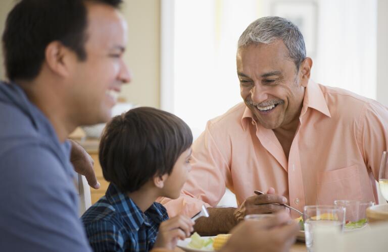 grandfather smiling at table with son and grandson