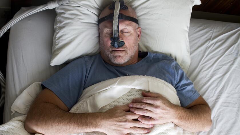 man sleeping in bed wearing cpap mask