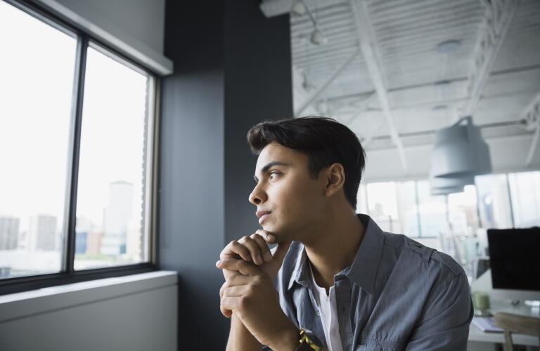young-businessman-staring-out-window-looking-serious