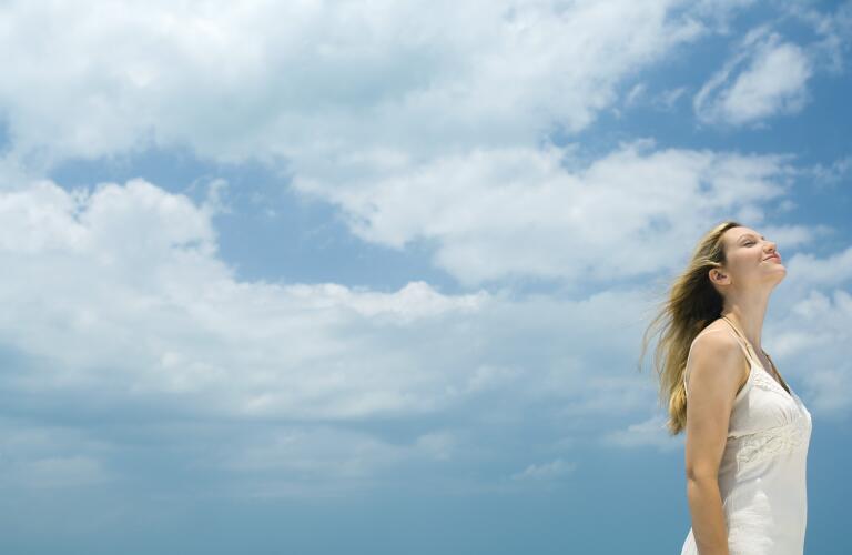 woman-standing-outside-breathing-fresh-air-with-sky-as-background