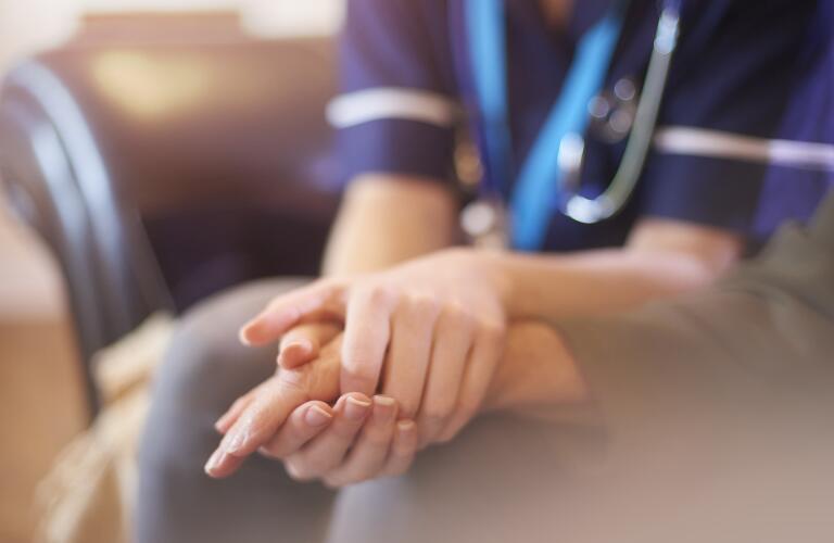 nurse consoling patient by holding hand
